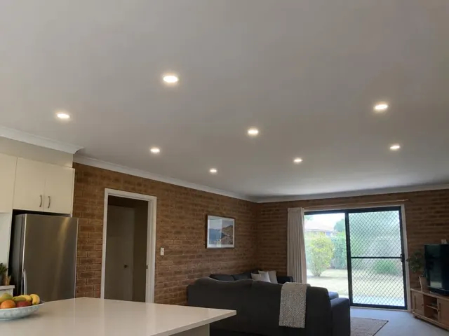 Ceiling with recessed LED downlights in a brick-walled living room with kitchen cabinets in Glenning Valley